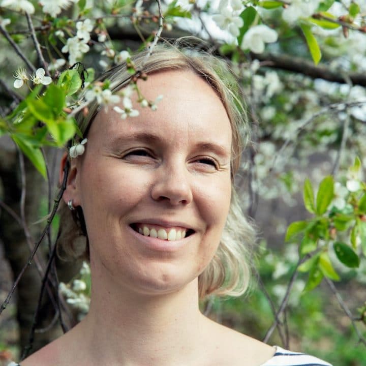 Sini Laaksonen etsii ratkaisuja MS-taudin hoitoon. Kuvassa Sini Laaksonen hymyilee kukkivan pensaan edessä.