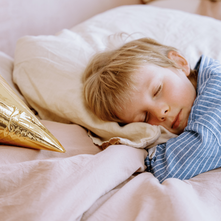 Kuvassa pieni vaaleatukkainen lapsi nukkuu siniraidallisessa yöasussa. ADHD univaikeus